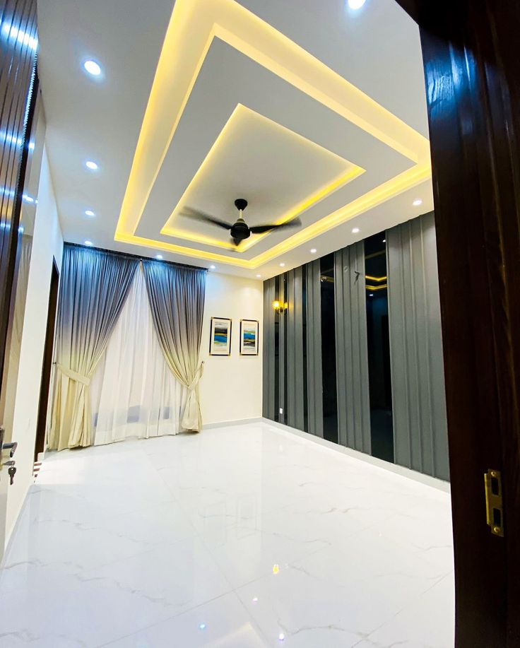 Salon avec faux plafond décoratif à double niveau et éclairage doux